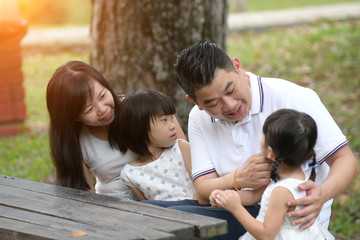 asian family sitting on the bench park