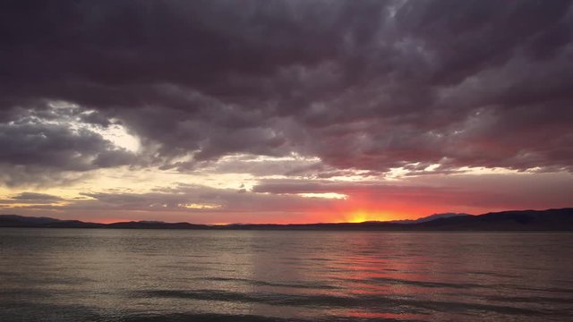Colorful sunset over Utah Lake on summer evening as the sky reflects in the water.