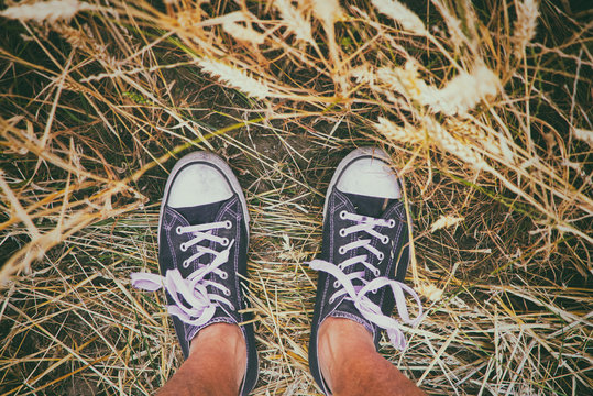Man wearing black and white sneakers and standing in golden wheat field.