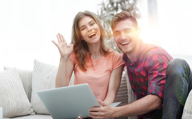 happy couple laughing ,sitting on the couch in front of the open laptop