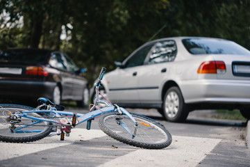 Bike lying on a pedestrian crossing with cars in the background