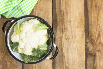 Fresh cauliflower in a colander on an old wooden table