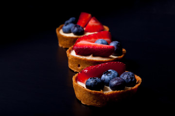 Berry tartlets with blueberries, strawberries and butter cream. Shallow depth of field. Selective focus