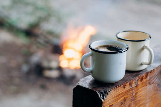 Two coffee cups  near campfire. Warm and cold. Camping.