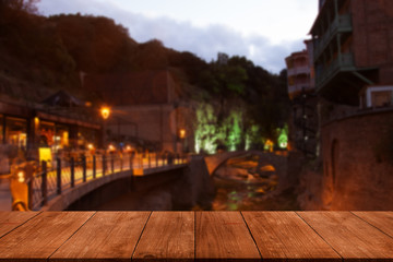 View from dark wooden gangway, table or bridge to the night Tbilisi. Collage