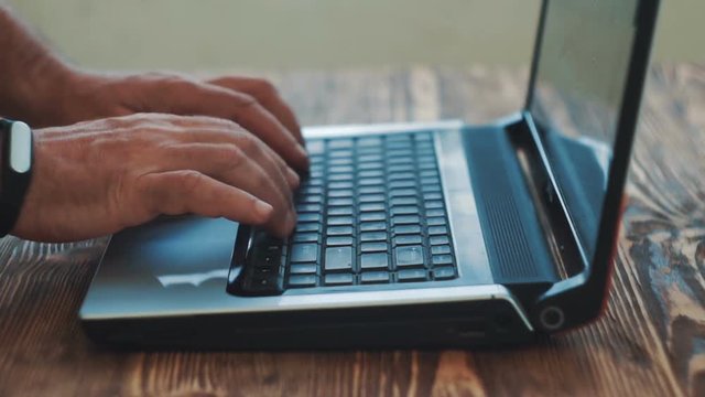 Man Fingers Taping Keyboard Notebook Computer. Close up.