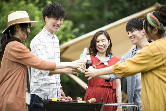 グランピングテントの前で乾杯をする若者たち