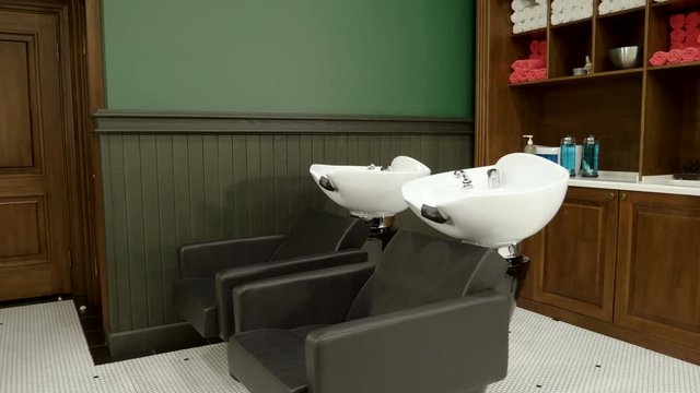 Two empty chairs with a wash basin at barbershop. 4K