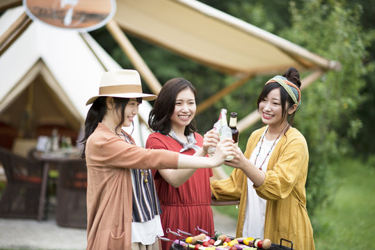 グランピングテントの前で乾杯をする若者たち