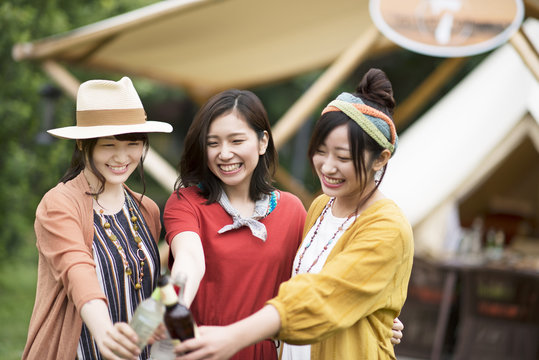 グランピングテントの前で乾杯をする若者たち