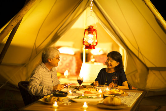 グランピングテントの前で食事をするシニア夫婦