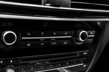 Obraz na płótnie Canvas Air conditioning button inside a car. Climate control AC unit in the new car. Modern car interior details. Car detailing. Black perforated leather interior. Black and white