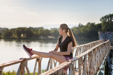 Sport and fitness. Young woman training outdoor at sunrise with urban background.
