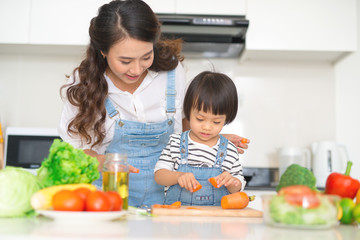 Mother with her daughter preparing lunch in the kitchen and enjoying together.