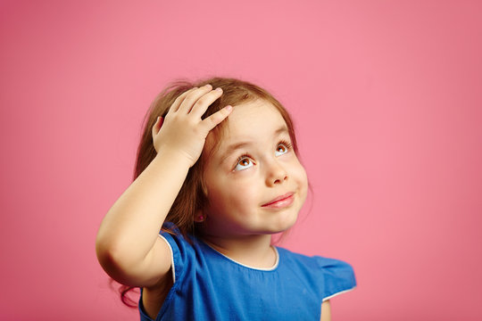 Cute children girl put her hand to head and looks up