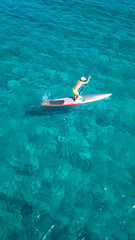 Aerial photo of man practicing SUP or Paddle board in crystal clear waters of Greek Aegean island