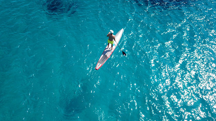 Aerial drone bird's eye view of man exercising sup board in turquoise tropical clear waters