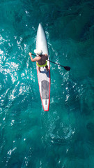 Aerial drone bird's eye view of man exercising sup board in turquoise tropical clear waters