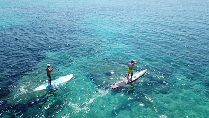 Aerial drone bird's eye view of man exercising sup board in turquoise tropical clear waters
