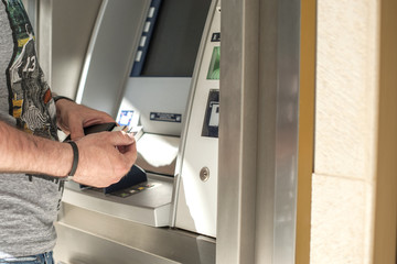 Man Uses a credit card at an ATM on the street. Operation with money. Modern payment technologies. Copy space,