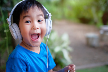 Kid listen music with headphone at home. Look excited expression face.