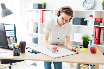 A young man with glasses and headphones draws a marker on the magnetic board.