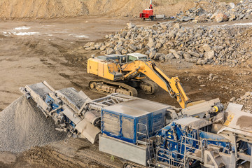 Stone crusher and excavator in an open pit mine