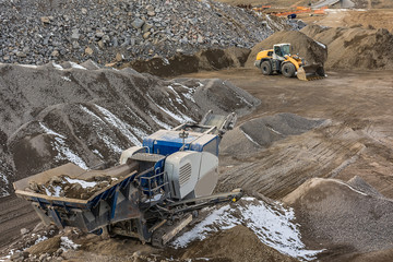 Stone crusher and excavator in an open pit mine