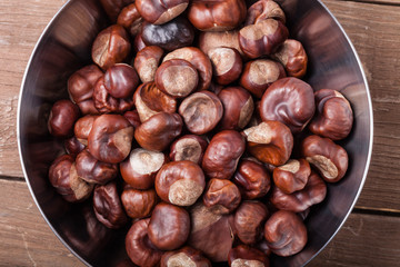 Chestnuts in a metal bowl on the old wooden background