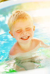 Fototapeta na wymiar Portrait of baby boy enjoying swimming in inflatable pool