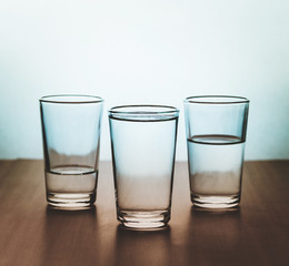 studio shot of three water glasses each one have more water than the other