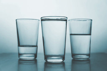 studio shot of three water glasses each one have more water than the other