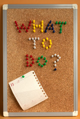 To do list written with colorful pins on corkboard