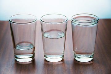 studio shot of three water glasses each one have more water than the other