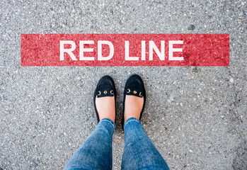 Danger. woman legs in black shoes standing behind the red line