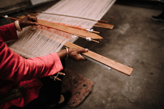 Woman weaving at loom with shuttle at workshop