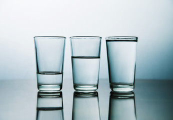 studio shot of three water glasses each one have more water than the other