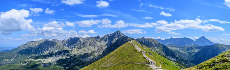 Mountain panorama of the Tatra Mountains from Kasprowy Wierch (Kasper Peak) with blue sky and clouds on a beautiful sunny day in Poland