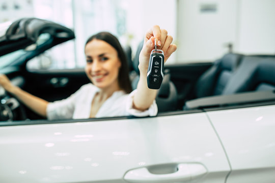 Cropped photo of young woman with car key in hand. Buying a car