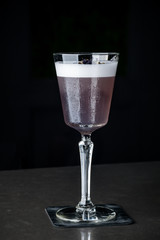 purple drink with blueberries in a glass on a high leg with ice