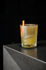 Yellow refreshing drink with lemon and mint in a glass of ice. Cocktail on a black background