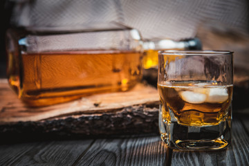glass of whiskey and a bottle of whiskey on a wooden background