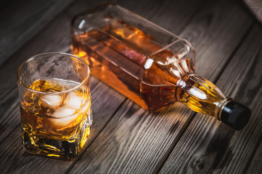 glass of whiskey and a bottle of whiskey on a wooden background