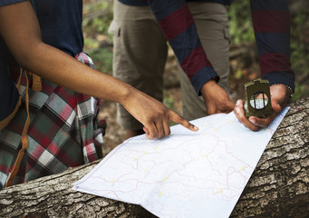 Trekking couple using map and compass in a forest