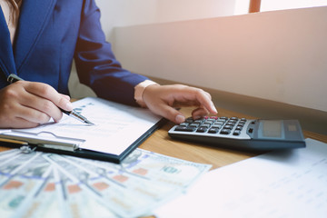 Businessman analyzing investment charts and pressing calculator buttons over documents. Accounting Concept.