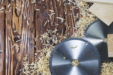 Two saw blades and pieces of wood on sawdust in the wood workshop.