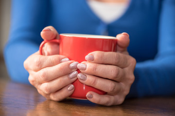 Woman's hands holding a mug of hot beverage