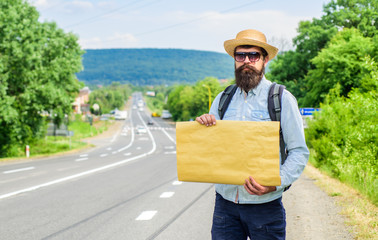 Short general directions. Man bearded hitchhiker stand at edge of road with blank paper sign, copy space. Benefits using sign with name destination. Cardboard sign with indication where you want go