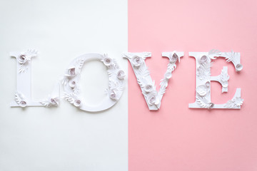 Photo inscription love made of leaves and flowers on white and pink background