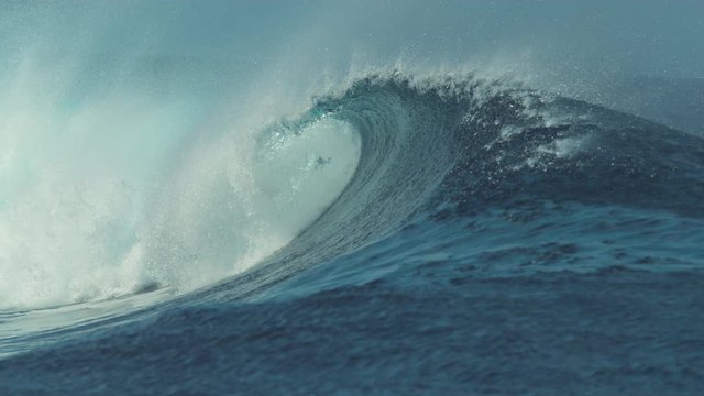 SLOW MOTION, CLOSE UP: Beautiful deep blue tube wave in the wild Pacific Ocean curls towards a remote island on a sunny day in summer. Spectacular shot of wild barrel wave coming from the exotic sea.
